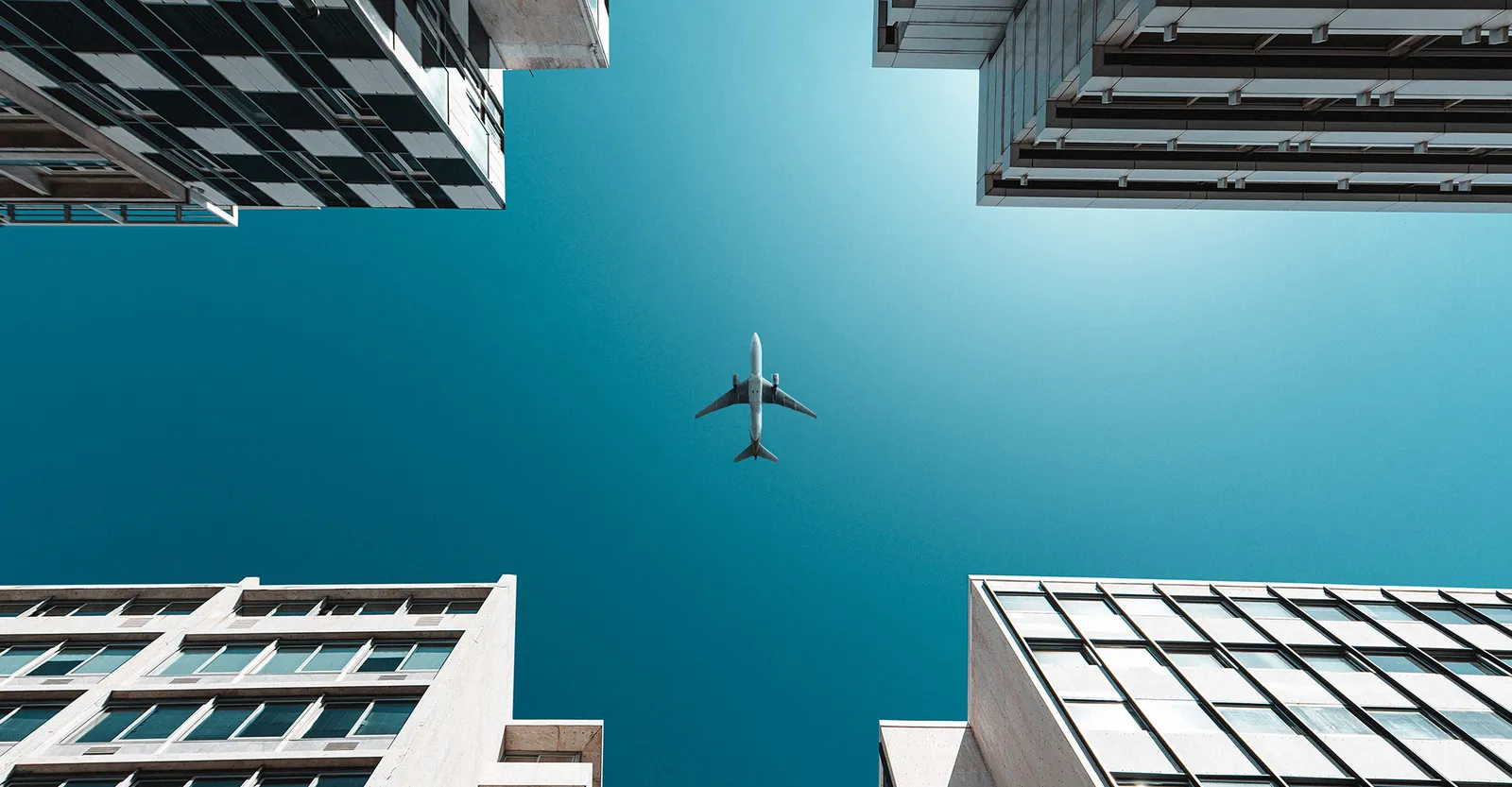 An airplane flying between high-rise buildings